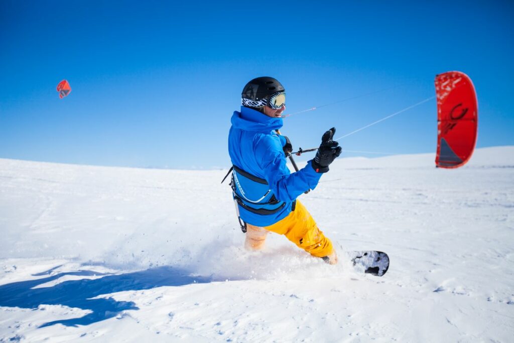 Pratique du kitesurf sur neige, sport insolite de glisse sur la neige
