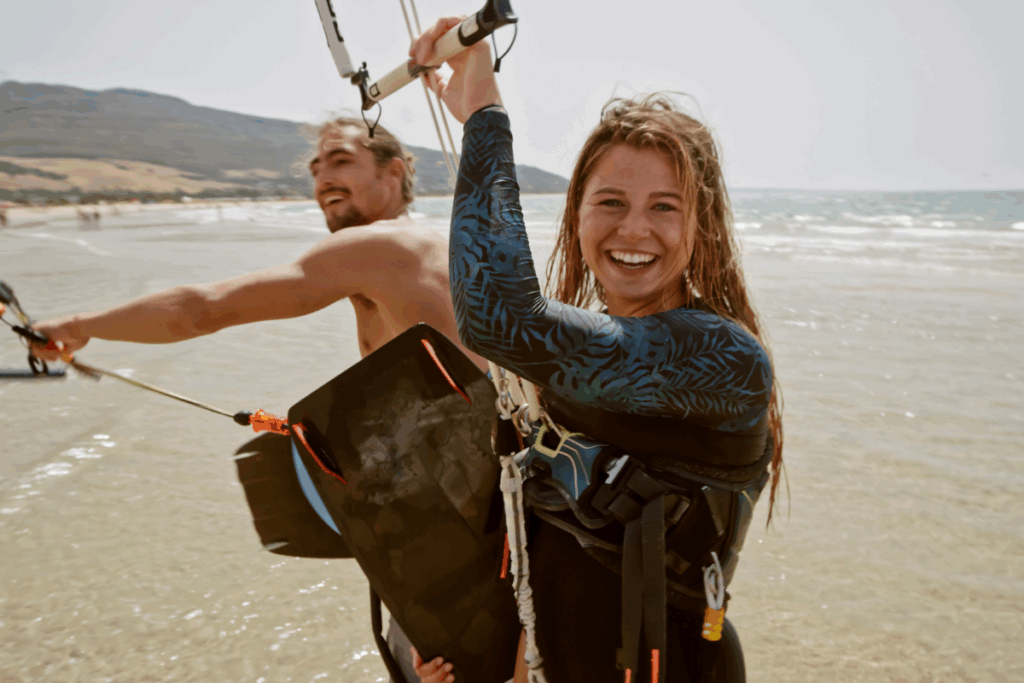 Deux kitesurfeurs souriants en bord de plage après une session