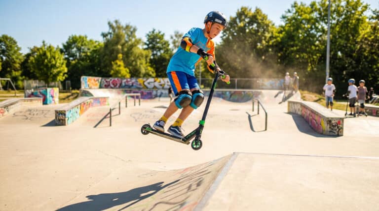 Enfant réalisant un saut en trottinette dans un skatepark