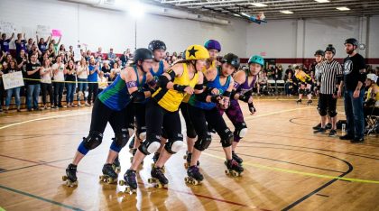 Équipe de roller derby en pleine action lors d’un match avec public et arbitres en arrière plan