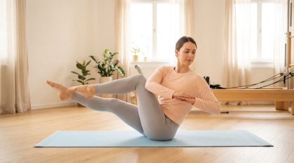 Femme pratiquant un exercice de pilates sur tapis dans un studio lumineux et minimaliste.