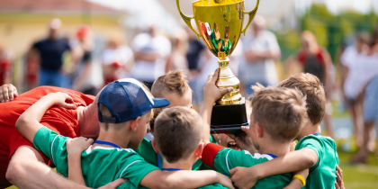 Groupe d’enfants en maillot vert tenant une coupe de vainqueur, symbole d’esprit d’équipe et de réussite sportive